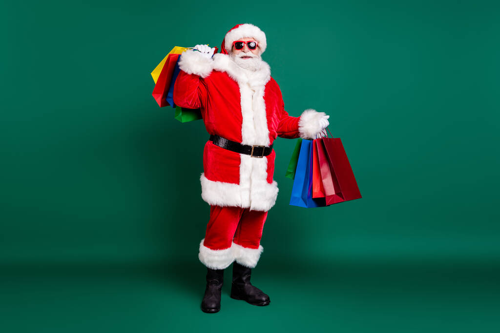 Kilolu, şişman, neşeli, Noel Baba Kuzey Kutbu 'nun vücut ölçülerinde. Elinde hediyeler, yeşil arka planda izole edilmiş sürpriz sipariş var. - Fotoğraf, Görsel