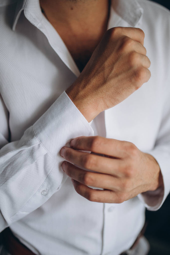 Мужская рубашка с пуговицами, мужчина в белой рубашке, утренний жених, руки мужчины крупным планом, белая рубашка на бизнесмене, рукав мужской пуговицы, бизнесмен надевает костюм - Фото, изображение