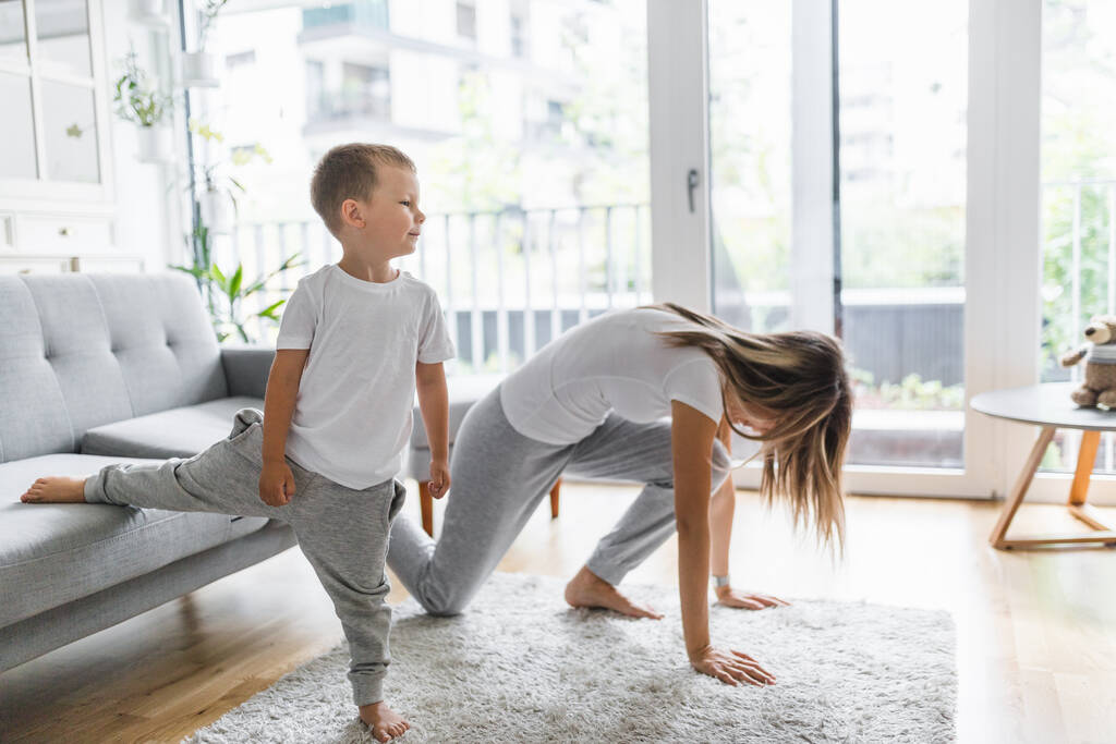 Mamá con su hijo pequeño haciendo ejercicio en la sala de estar - Foto, imagen