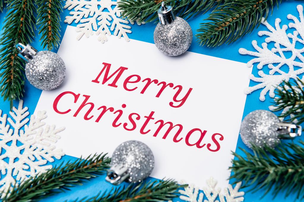 雪の結晶、銀の泡と青い背景に陽気なクリスマスカードとスプルースのトップビュー - 写真・画像