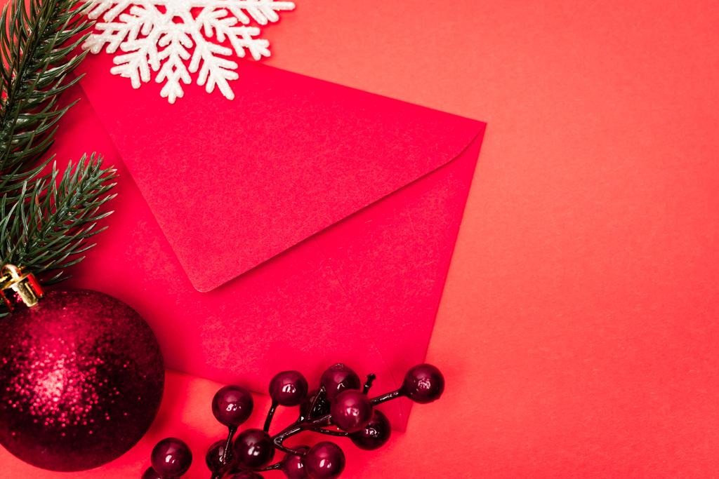 верхний вид рождественского украшения и конверт на красном фоне - Фото, изображение