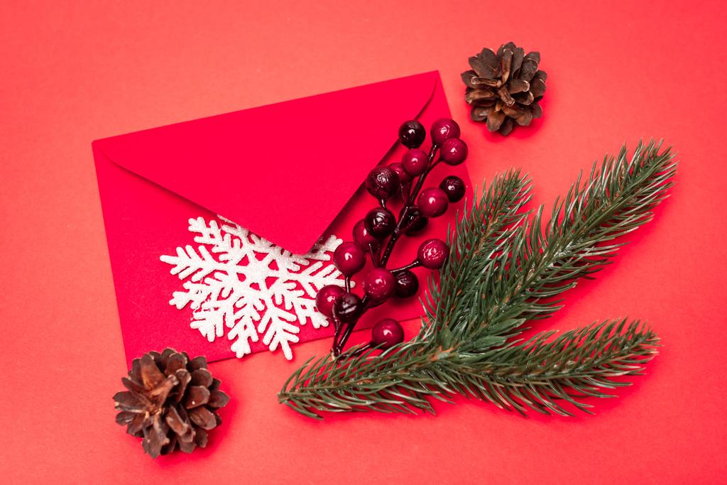 赤い背景にクリスマスの装飾と封筒のトップビュー - 写真・画像