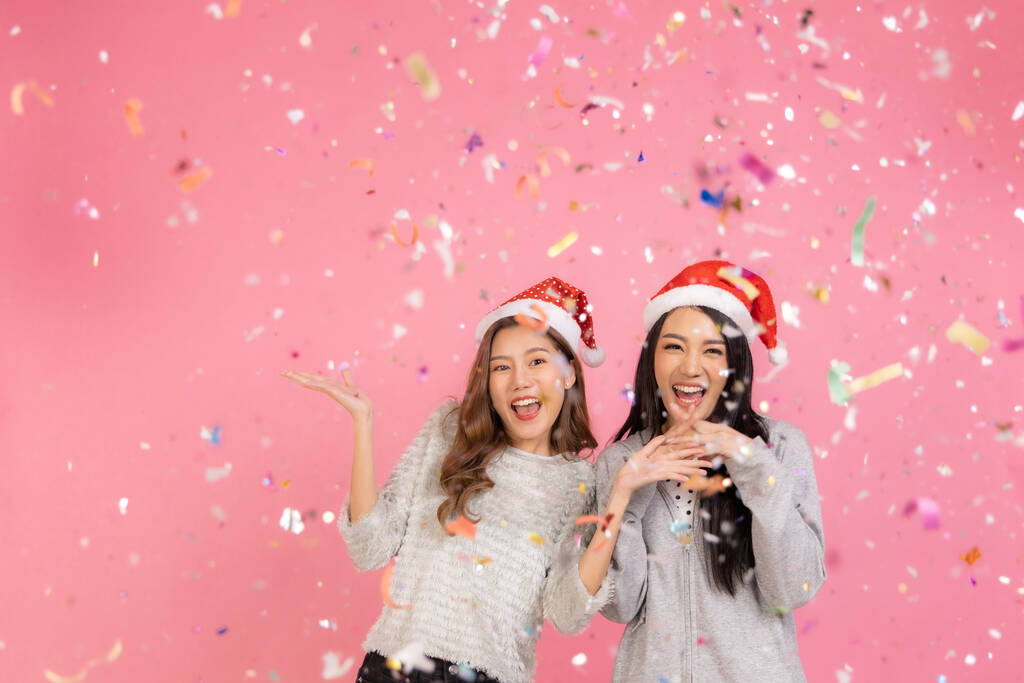 Retrato de dois adorável bonito asiático mulheres no Natal chapéus olhando para câmera isolada sobre rosa background.Attractive asiático mulher sorriso no Natal, ano novo, dia dos namorados, aniversário celebração conceito. - Foto, Imagem