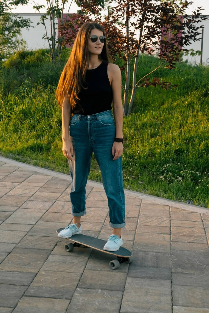młoda brunetka kobieta jazda na deskorolce w parku w lecie - Zdjęcie, obraz