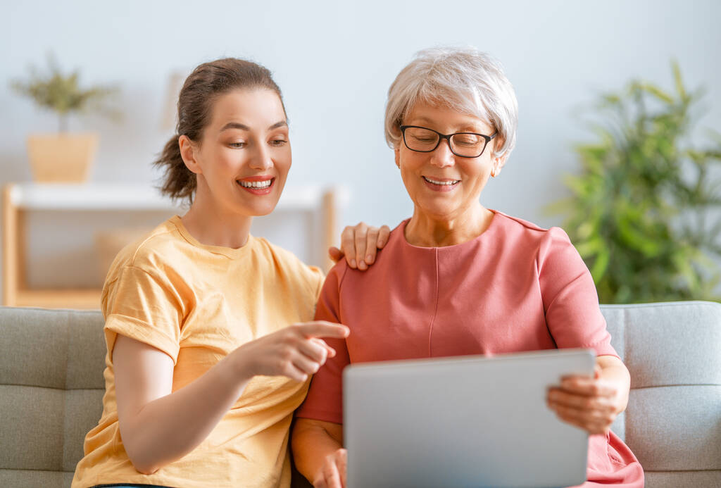 Jonge en oudere vrouwen gebruiken laptop pc. Dochter is het helpen van moeder hebben plezier thuis te blijven. - Foto, afbeelding