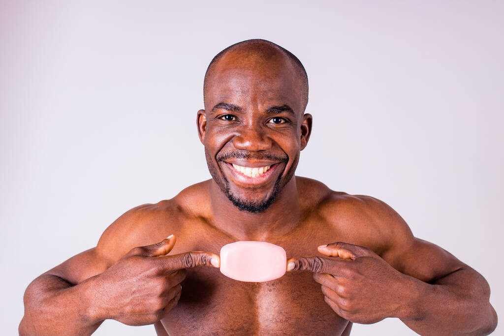 African man holds and show a piece of wet soap in studio white background - Photo, Image