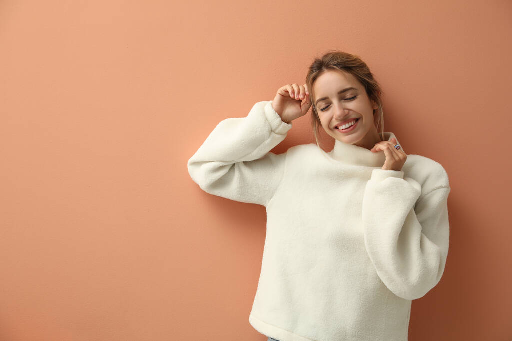 Beautiful young woman wearing knitted sweater on light brown background. Space for text - Photo, Image