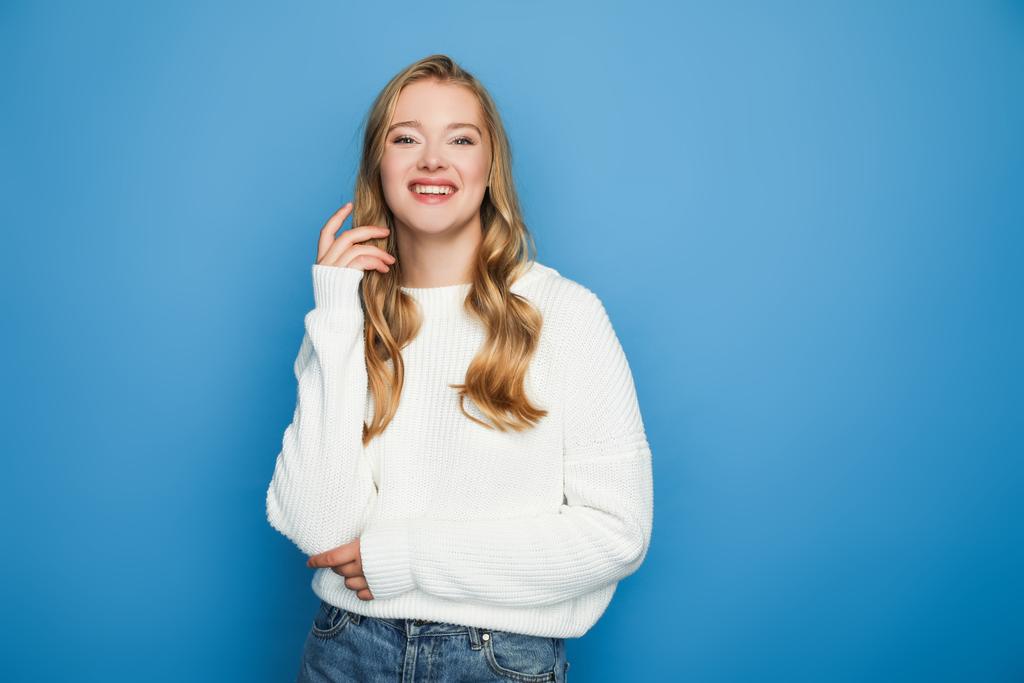 happy blonde beautiful woman in sweater isolated on blue background - Photo, Image