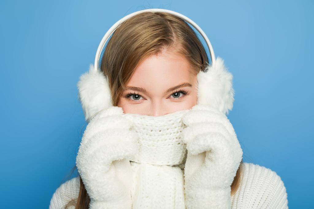 青い上に隔離されたスカーフで顔を覆う冬の白い服の美しい女性 - 写真・画像