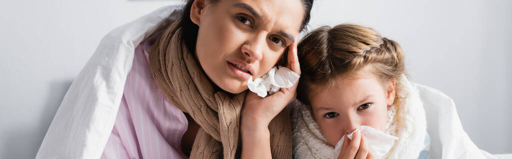 mujer enferma con hija con servilletas de papel mirando a la cámara, pancarta - Foto, imagen