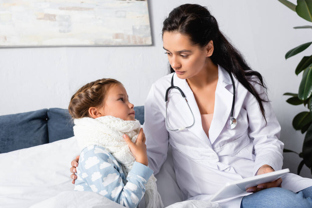 sairas lapsi koskettaa kurkkukipu lähellä lääkäri tilalla digitaalinen tabletti - Valokuva, kuva