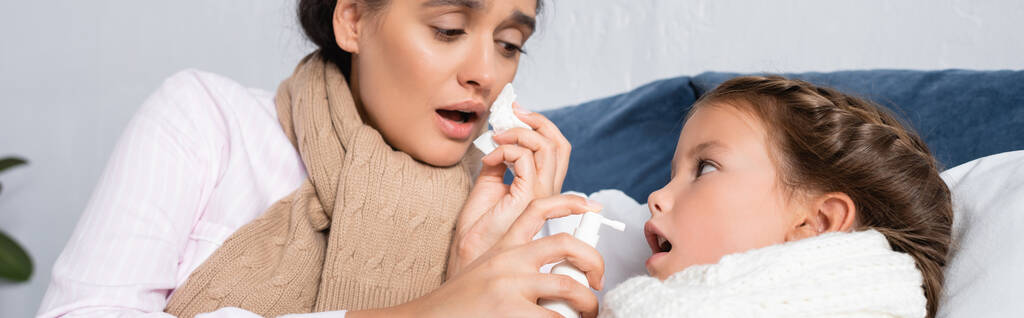 mujer enferma sosteniendo spray de garganta cerca de hija enferma, pancarta - Foto, imagen