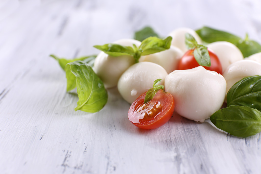 Tasty mozzarella cheese with basil and tomatoes, on wooden table - Photo, Image