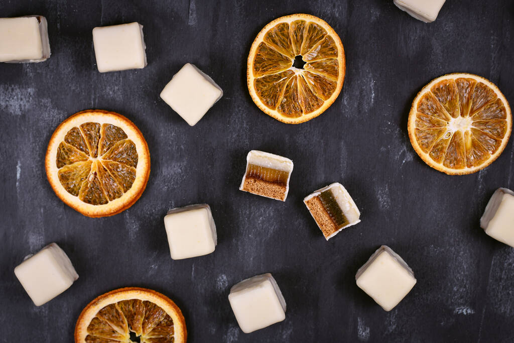 Tradiční německé sladkosti zvané "Dominosteine" a plátky pomeranče. Vánoční jídlo skládající se z perníku, pomerančové želé a marcipánové vrstvy pokryté bílou čokoládovou polevou - Fotografie, Obrázek