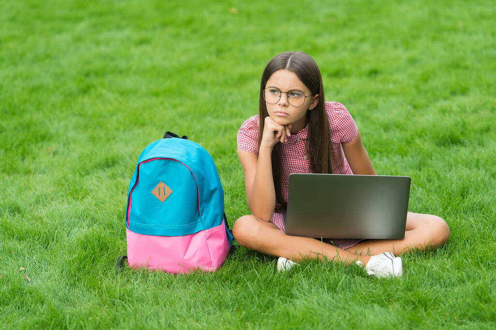 de vuelta a la escuela. adolescente uso de la computadora en la hierba verde en el parque. niño con mochila y cuaderno. nueva tecnología en la vida moderna. Estudia. niño descontento pensando trabajando en el portátil. educación en línea - Foto, imagen