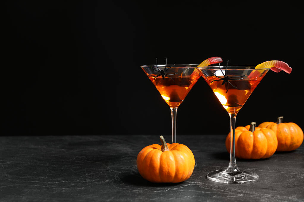 Decorated glasses with drinks on grey table, space for text. Halloween celebration - Photo, Image