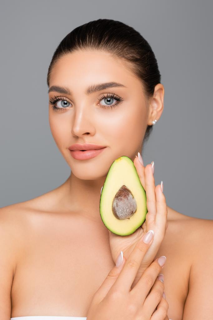 woman with naked shoulders and avocado half isolated on grey - Photo, Image