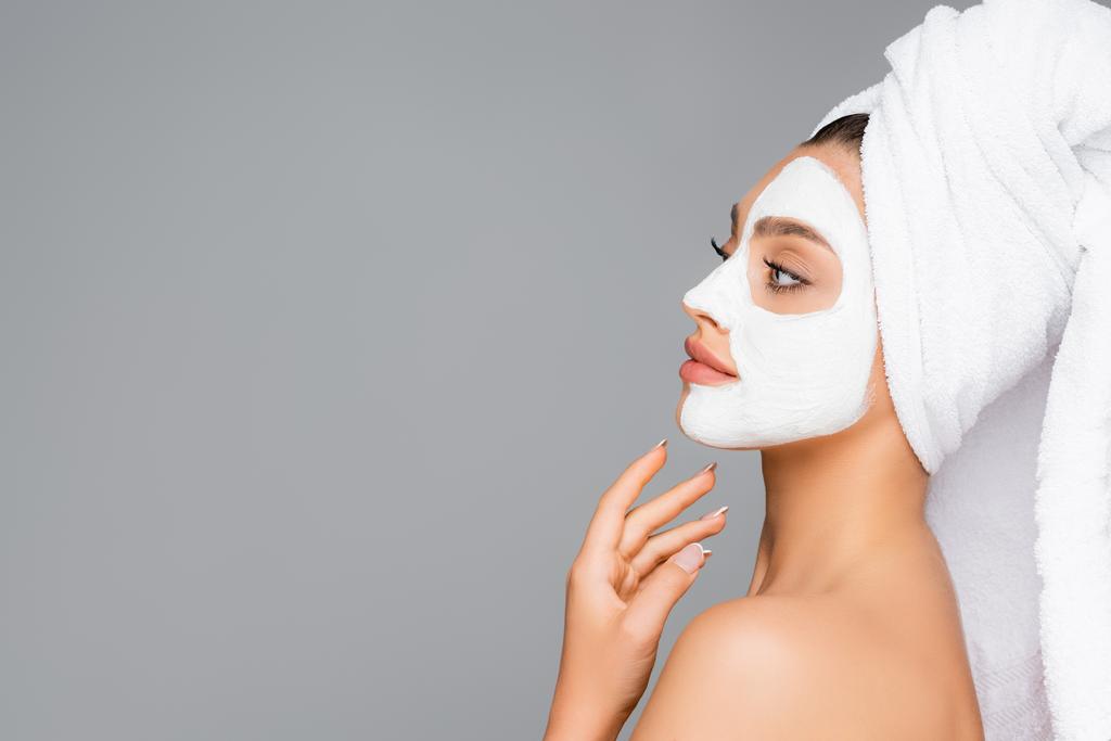 side view of woman with towel on head and clay mask on face isolated on grey - Photo, Image