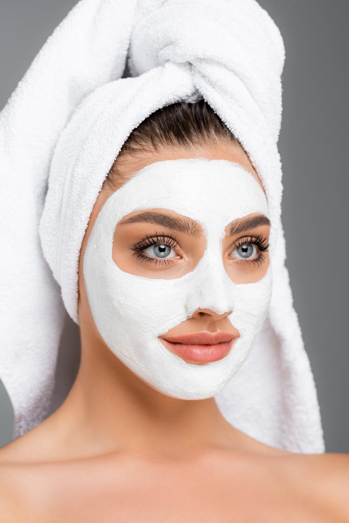 kobieta z ręcznikiem na głowie i glinianą maską na twarzy odizolowana na szaro - Zdjęcie, obraz