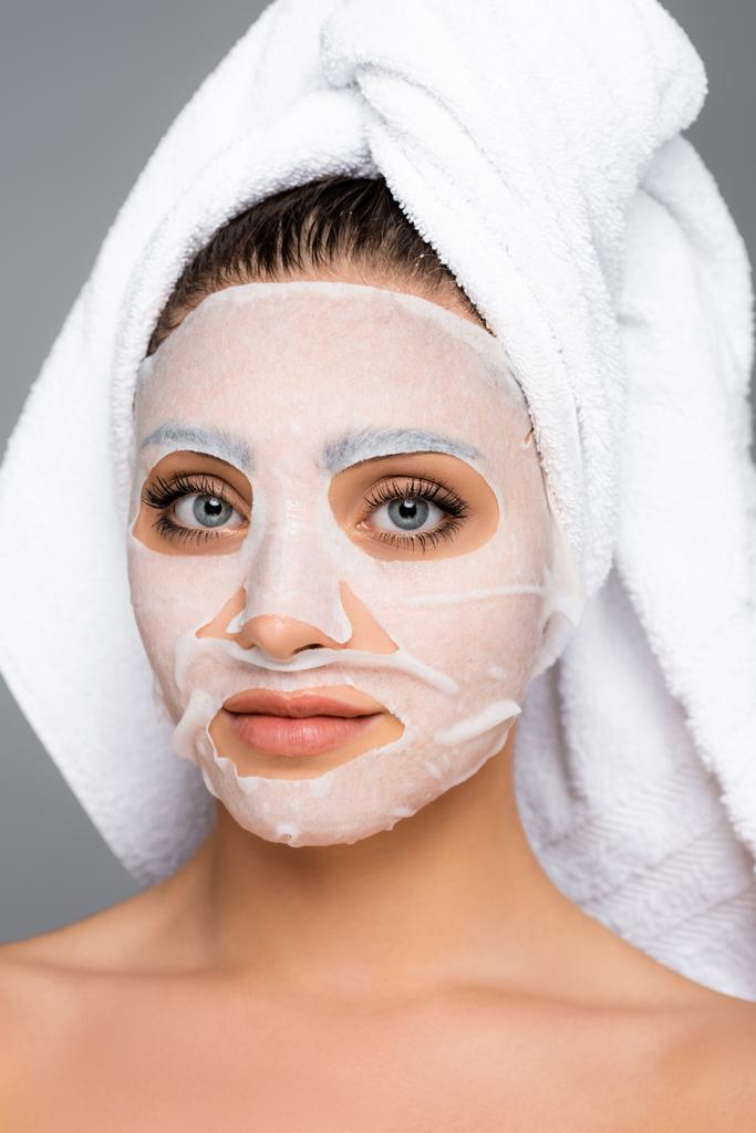 kobieta z ręcznikiem na głowie i arkusz maski na twarzy odizolowany na szaro - Zdjęcie, obraz