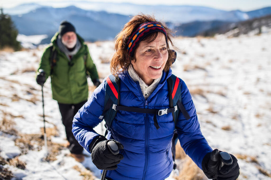 Idős pár skandináv sétapóznák túrázás havas téli természet. - Fotó, kép