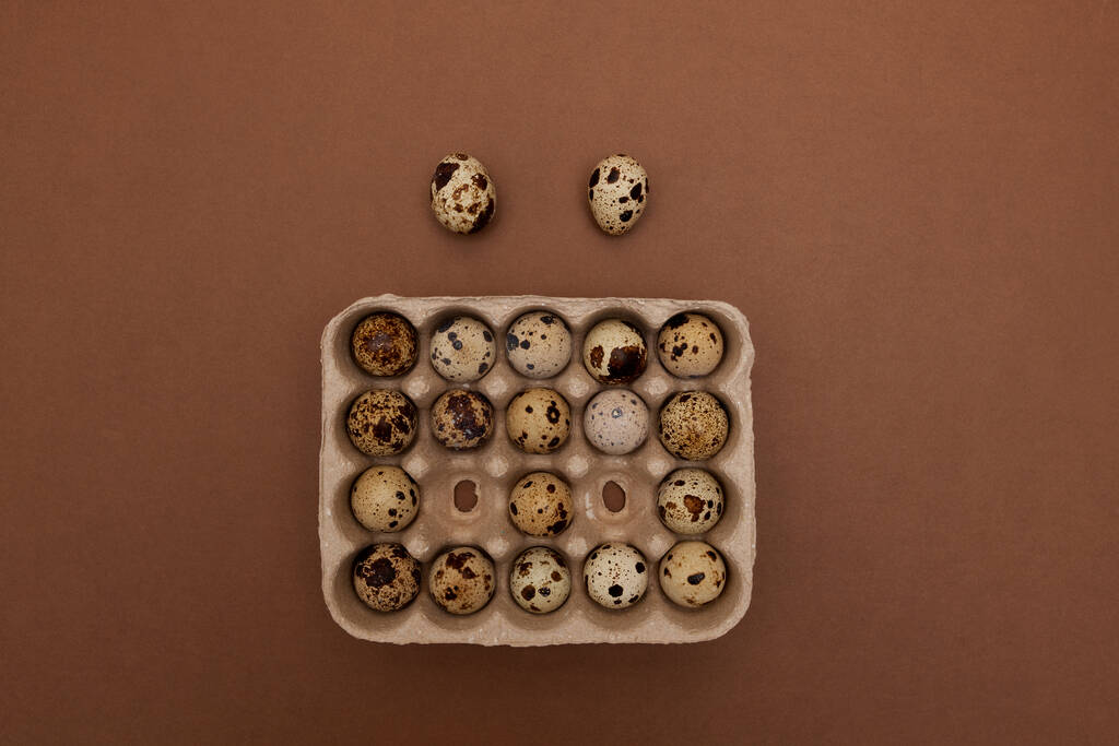 Quail eggs in package on brown background. Top view, copy space.  - Photo, Image