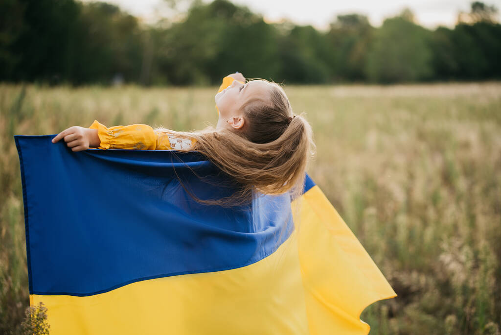 フィールドにウクライナの女の子青と黄色のフラグ。ウクライナの独立記念日。憲法の日だ。8月24日。愛国的な休日. - 写真・画像