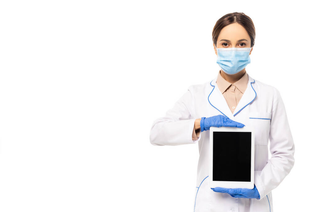 Doctor in latex handschoenen en medisch masker tonen digitale tablet met blanco scherm geïsoleerd op wit - Foto, afbeelding