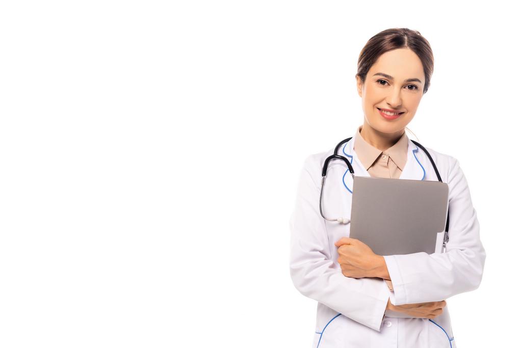 Usmívající se lékař v bílém plášti drží papírové složky izolované na bílém - Fotografie, Obrázek
