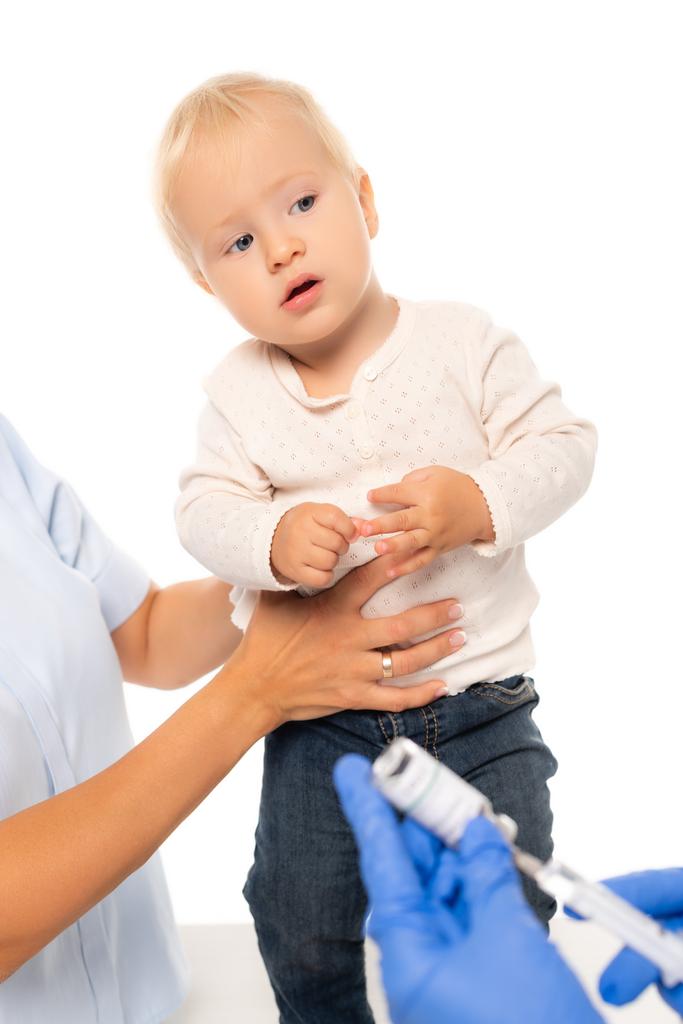 Selektiver Fokus des Vaters hält Jungen in der Nähe von Kinderarzt mit Impfstoff und Spritze isoliert auf weiß - Foto, Bild