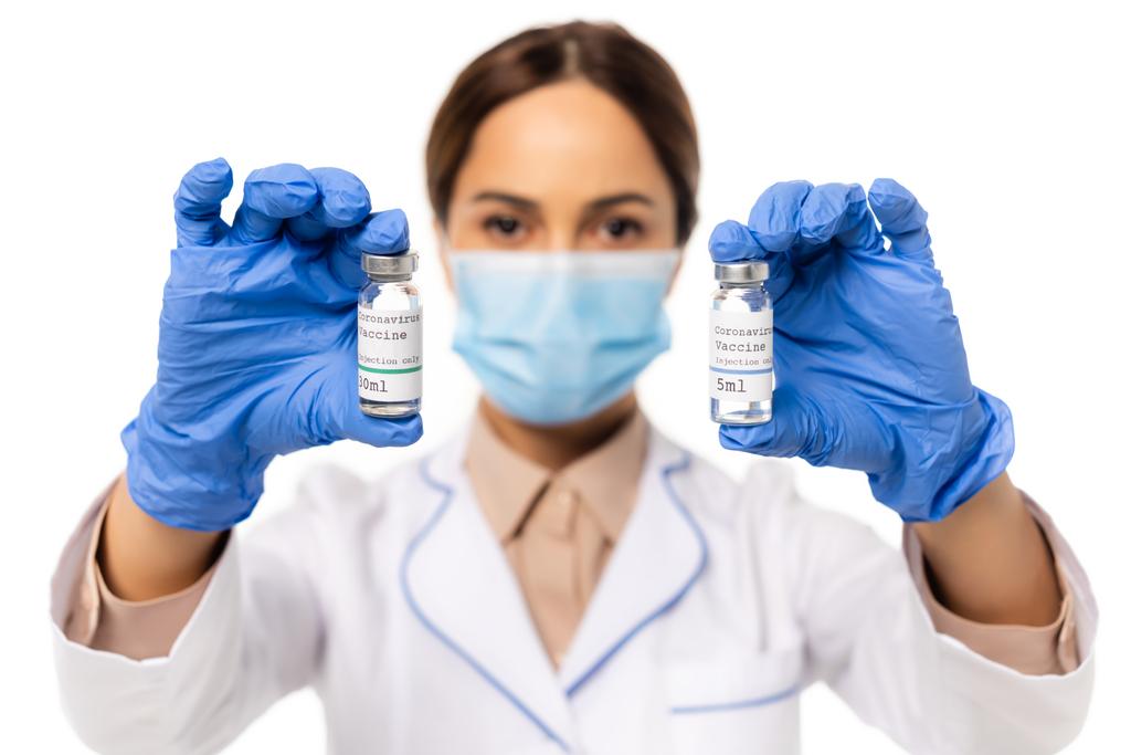 白い上に隔離されたコロナウイルスワクチンのレタリングと瓶を保持ラテックス手袋の医師の選択的な焦点 - 写真・画像