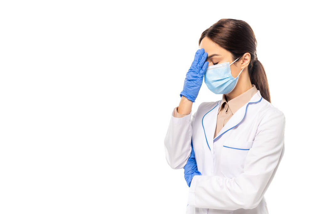 Γιατρός με ιατρική μάσκα και γάντια λατέξ που αγγίζουν το μέτωπο απομονώνονται σε λευκό - Φωτογραφία, εικόνα