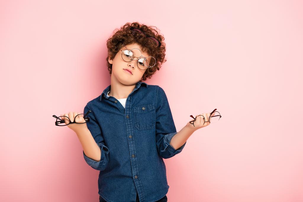 menino confuso segurando monte de óculos em rosa   - Foto, Imagem