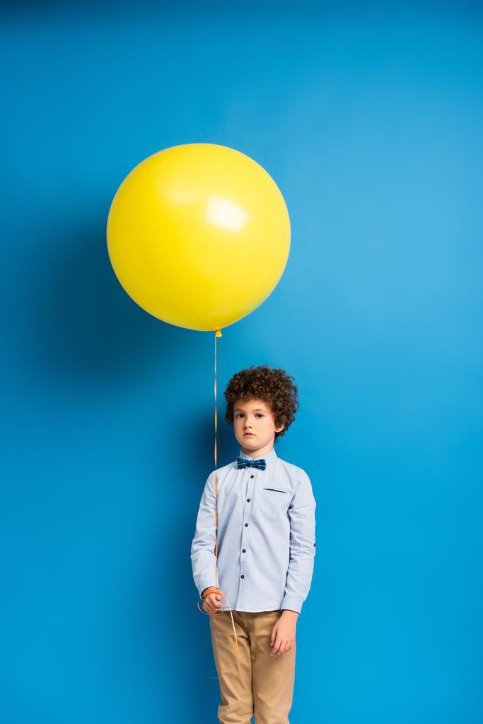 мальчик в рубашке и галстуке с большим жёлтым шариком на синем - Фото, изображение