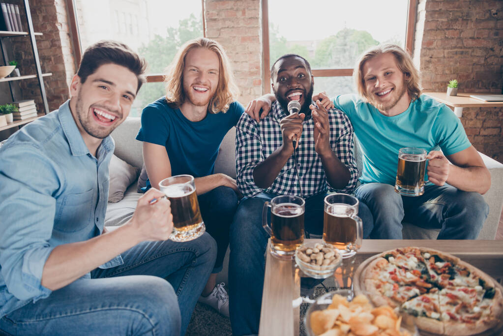 Portré a legjobb barátok férfi összejövetel ülni hangulatos kanapé tartani pint ital bögre énekelni dal karaoke a házban beltérben - Fotó, kép