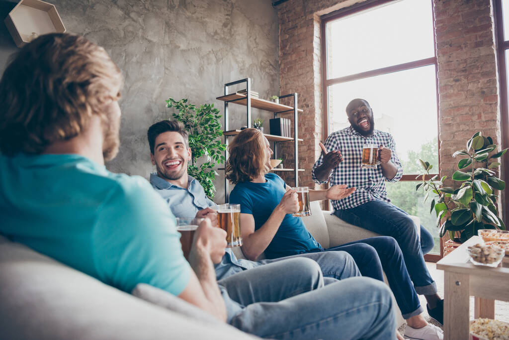 陽気な4人の男の仲間の肖像は、屋内のアパートで話題のニュースをお楽しみくださいdivanホールドマグカップ飲料ビールに座る - 写真・画像