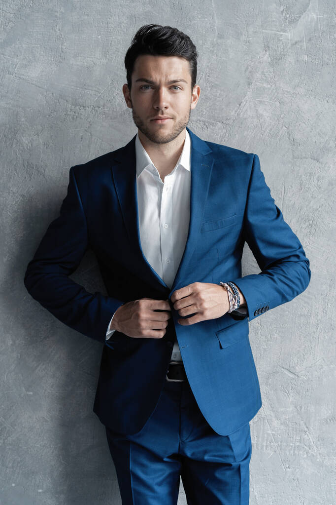 Красивый мужчина носить синий костюм изолированы на сером фоне. - Фото, изображение