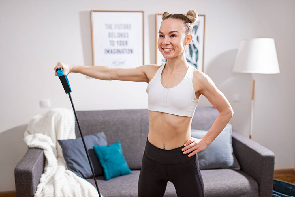 Cheerful woman exercising with resistance band at home - Photo, Image