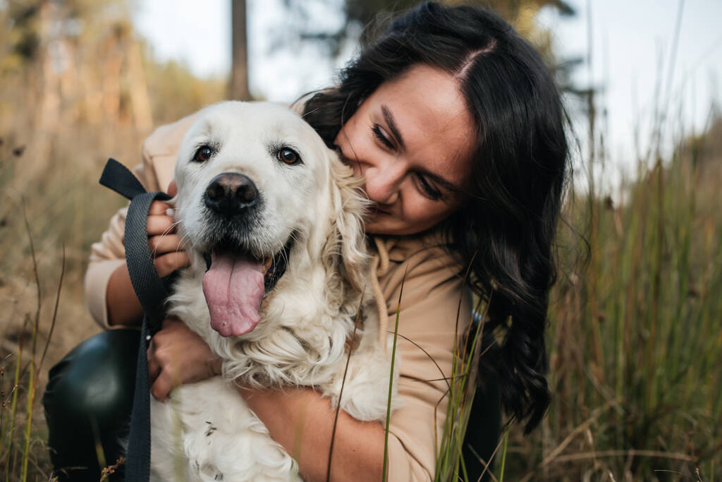 Mädchen umarmt Golden Retriever Hund auf dem Feld - Foto, Bild
