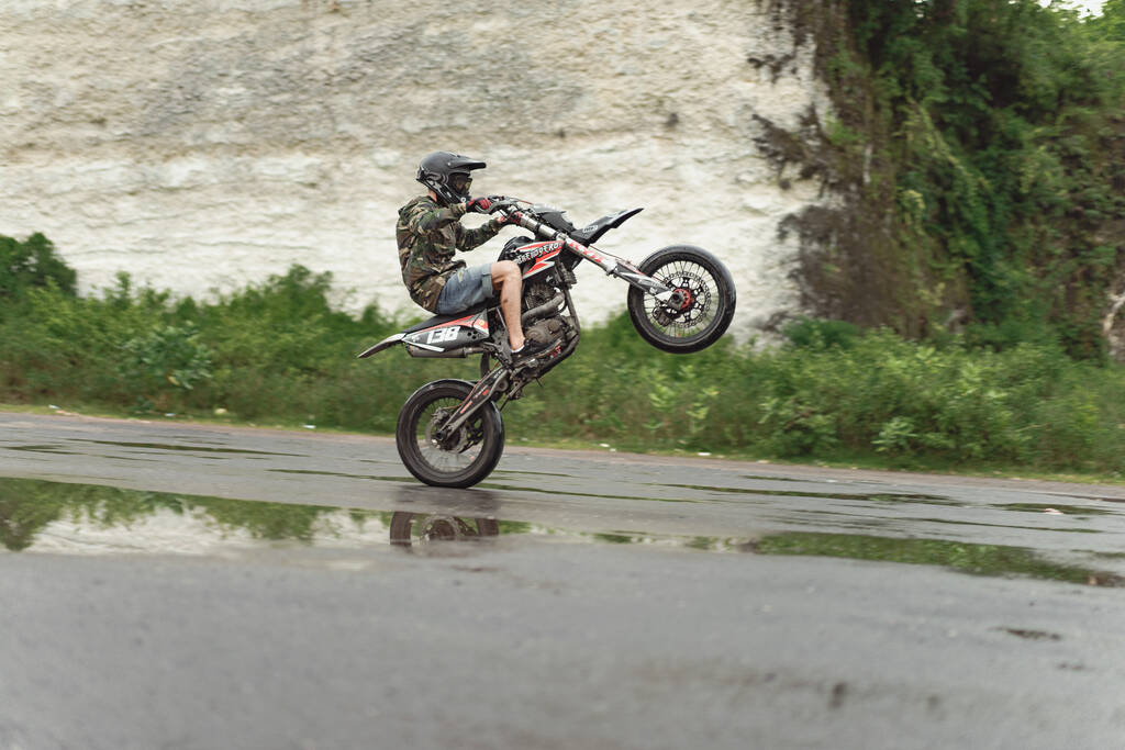 Een man op een motor die stunts doet. op een motorfiets op één wiel. - Foto, afbeelding