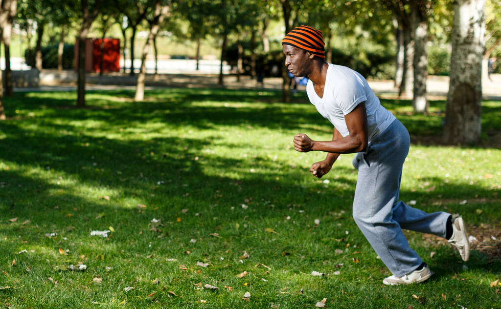 Atlético afro-americano homem correndo na grama durante o treino no parque - Foto, Imagem