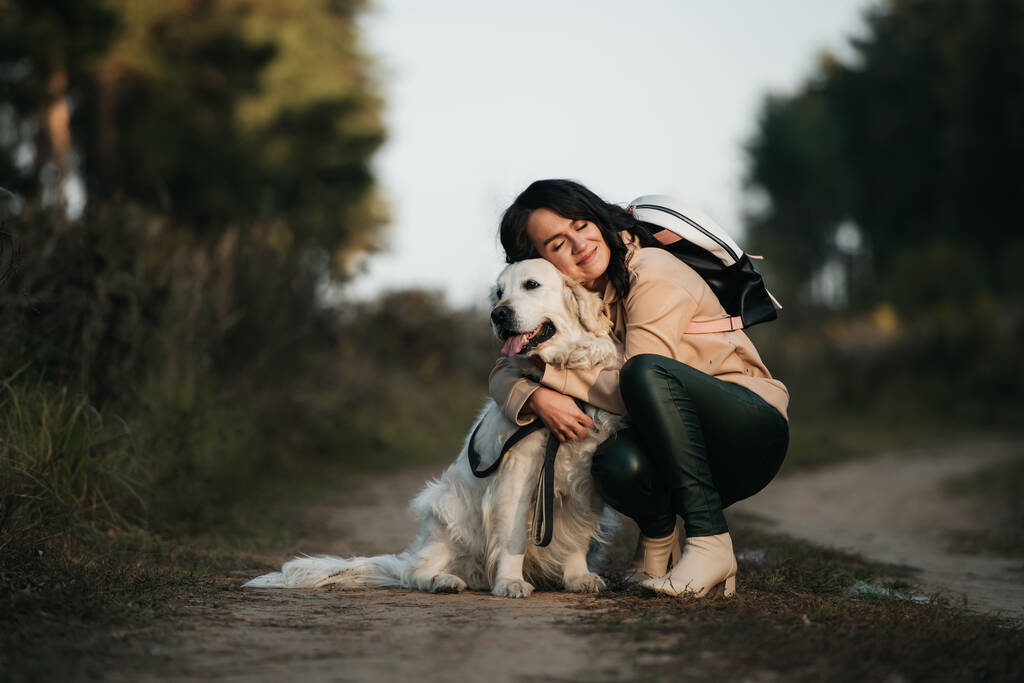 meisje knuffelen een golden retriever hond in het bos - Foto, afbeelding