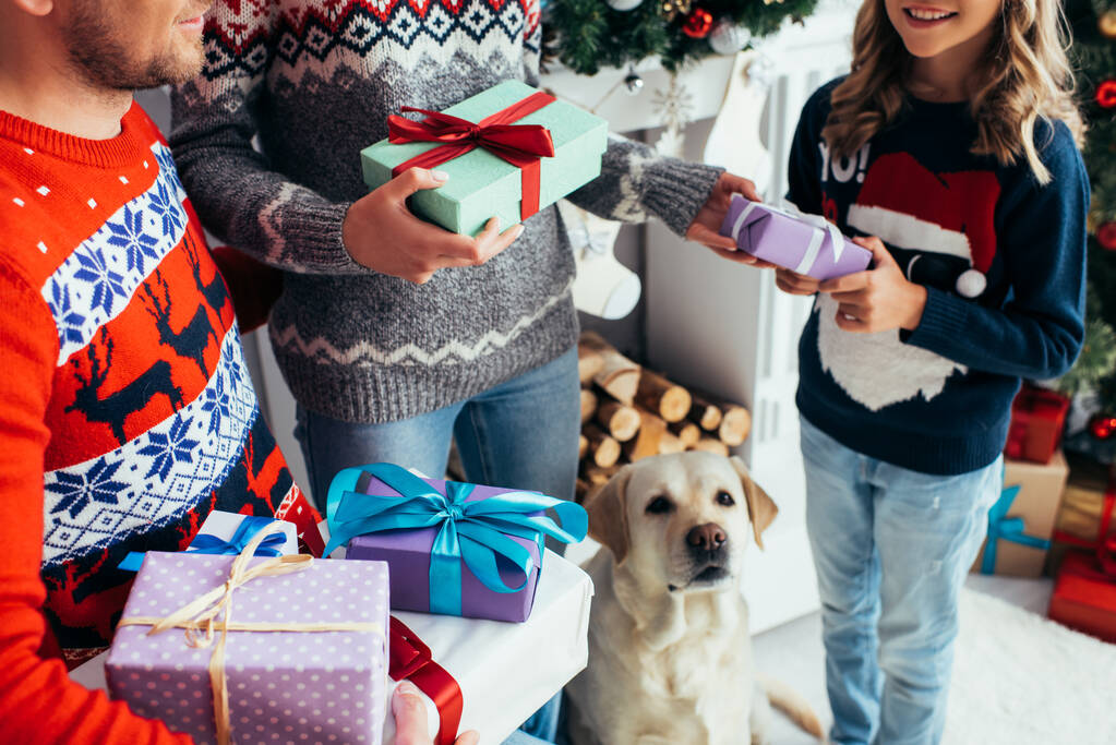 Mutlu kız ve köpeğin yanında Noel 'de hediyeler tutan ebeveynler.  - Fotoğraf, Görsel