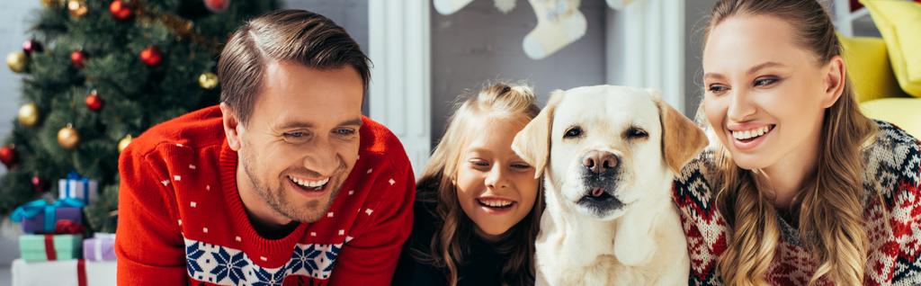 クリスマスに娘と犬の近くでラップトップで映画を見ている楽しい親バナー - 写真・画像