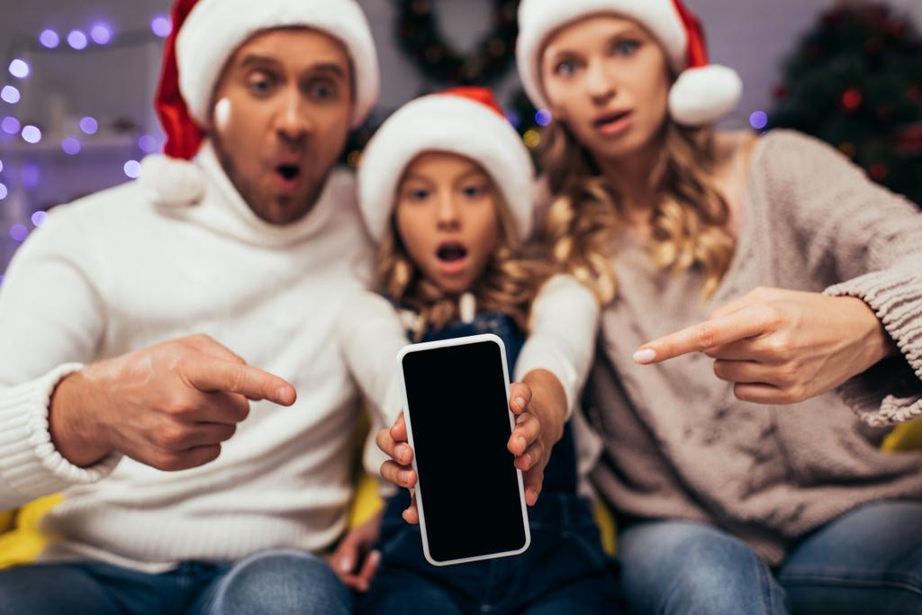 smartphone avec écran blanc et famille floue et choquée en arrière-plan - Photo, image