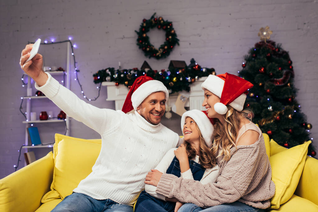 iloinen perhe joulupukki hatut ottaen selfie koristeltu olohuone  - Valokuva, kuva