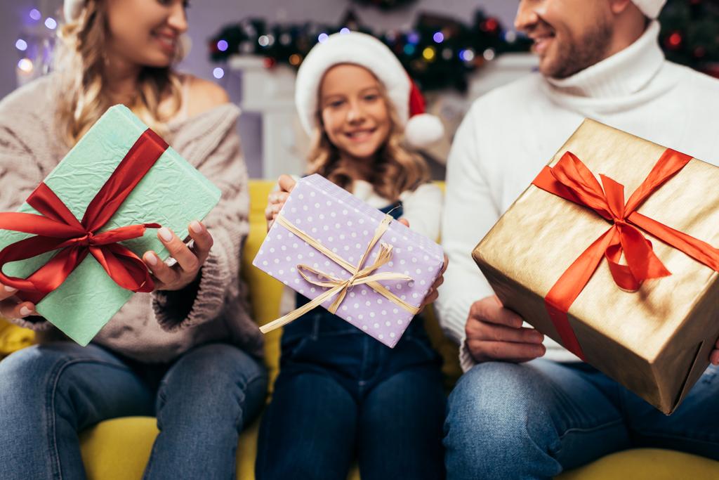 Рождественские подарки в руках радостной семьи на размытом фоне - Фото, изображение
