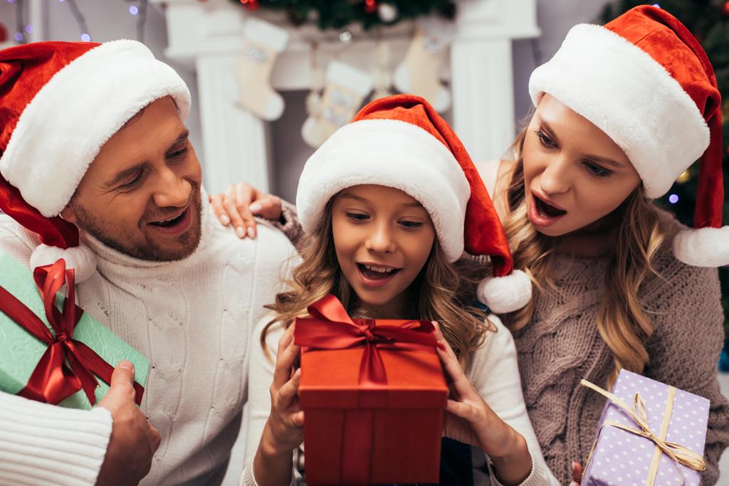 excited kid holding christmas present near parents - Photo, Image
