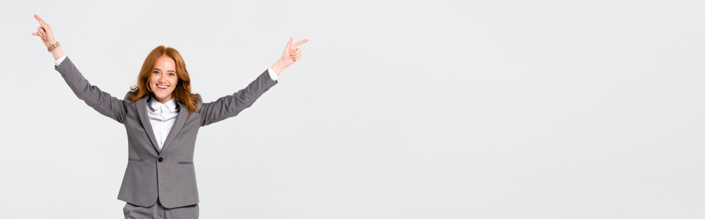 Cheerful businesswoman pointing with fingers isolated on grey, banner  - Foto, imagen