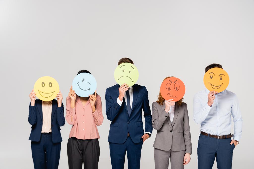 Empresarios multiétnicos sosteniendo tarjetas con emociones aisladas en gris - Foto, imagen